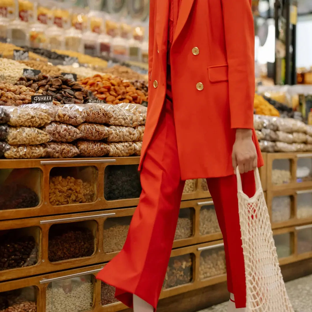 woman in red pant suit with string bag shopping in supermarket